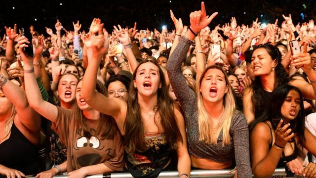 Young women cheering in the crowd at a music event