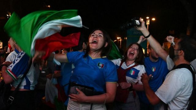 Supporters of the Italian national football team celebrate after Italy beat England 3-2 on penalty shootout to win the the UEFA EURO 2020 final football match, at the Fori Imperiali fanzone, in Rome