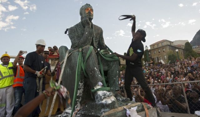 Students attack the defaced statue of British mining magnate and politician, Cecil John Rhodes, as it is removed by a crane from its position at the University of Cape Town on April 9, 2015, in Cape Town.