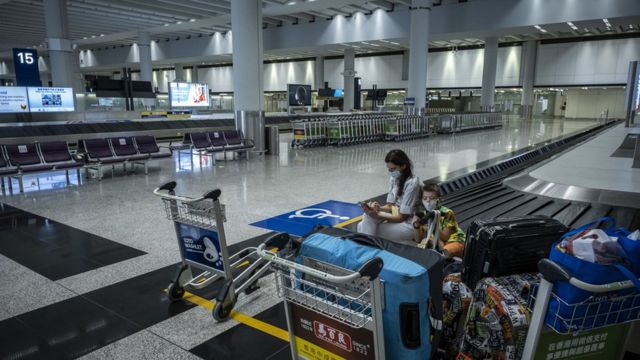 A mother and son wait at the empty arrivals baggage hall in Terminal 1 of Hong Kong International Airport (9/7/2022)