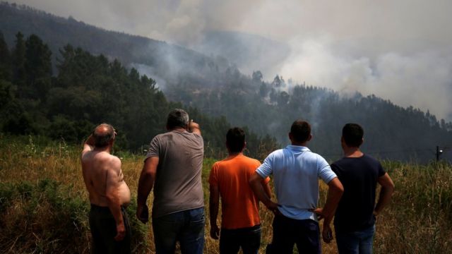 Homens observam incêndio em Portugal à distância