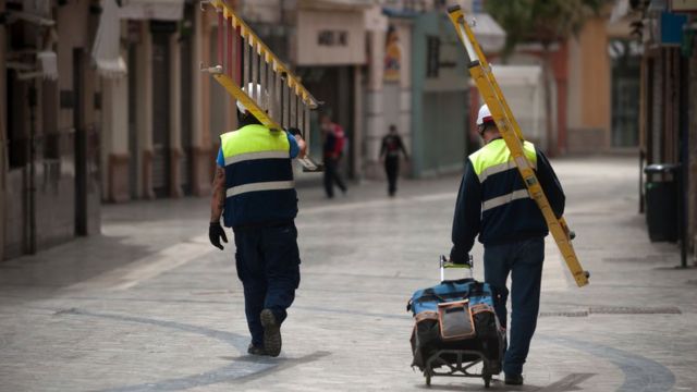 Dos obreros de la construcción caminan por una calle de Madrid.
