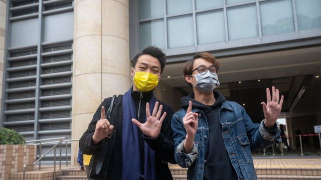 2020/12/17: Pro-democracy activists Jimmy Sham Tsz-kit (L) and Figo Chan (R) make gestures outside of West Kowloon Courts before they attend court hearing for their charges of illegal assembly from a protest on July 1 this year.