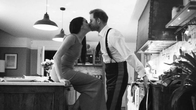 Uma foto do documentário Harry & Meghan na Netflix, mostrando o casal se beijando na cozinha