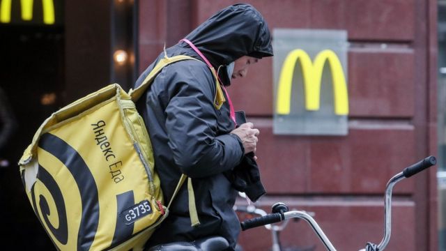 Сотрудник Яндекс-еда на фоне McDonald's