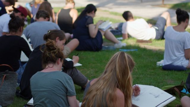 Estudiantes universitarios leyendo sobre el césped.