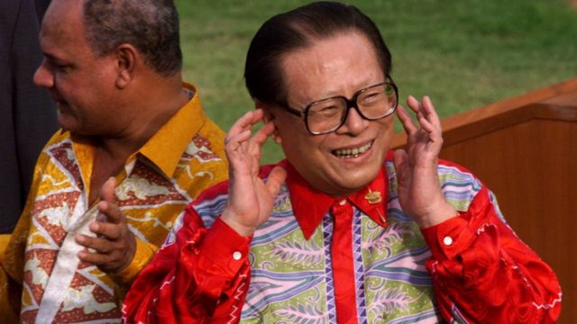 1998年11月18日，亚太经济合作组织领导人在马来西亚举行的峰会结束并发表声明后，中国国家主席江泽民将手指放在耳边回应媒体的呼喊。
