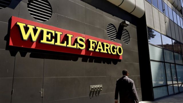 Un hombre camina frente a una sucursal de Wells Fargo.