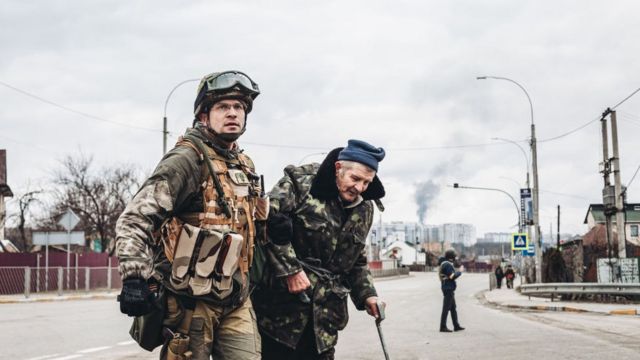 Un soldado ucraniano ayuda a un anciano en su escape de Irpín
