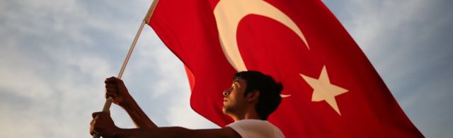 A man waves a national flag as thousands of people march to protest against the deadly attacks on Turkish troops, in Izmir, Turkey on 9 September, 2015