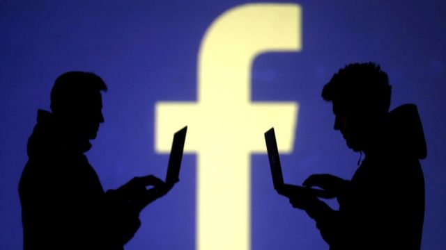 Facebook logosu önündeki bilgisayar kullanıcıları