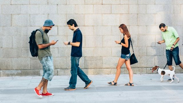 personas caminando con celular