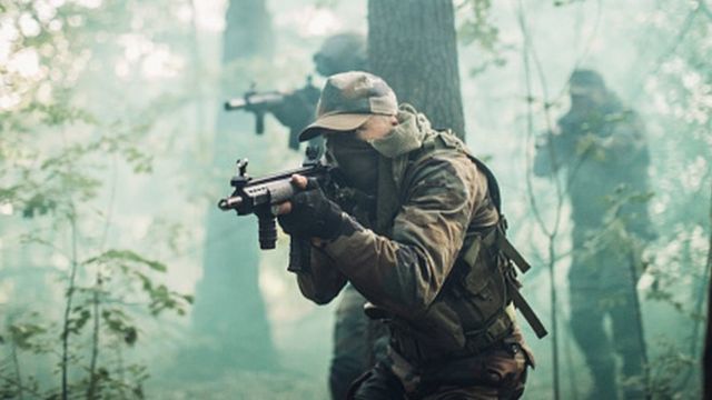 Des soldats en tenue de camouflage, armés de fusils, en pleine nature, en mission.