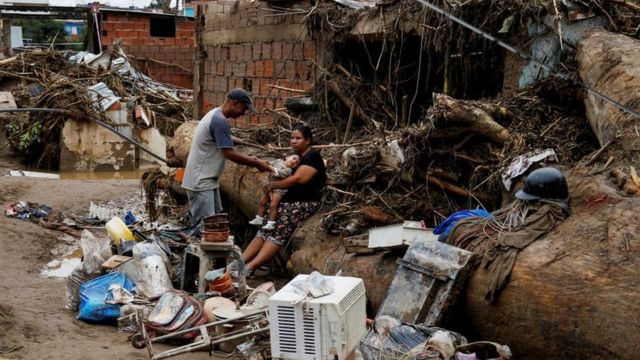 Una familia sentada alrededor de sus pertenencias tras las inundaciones en Las Tejerias.