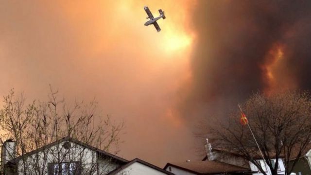 Smoke fills the air as a plane flies over Fort McMurray