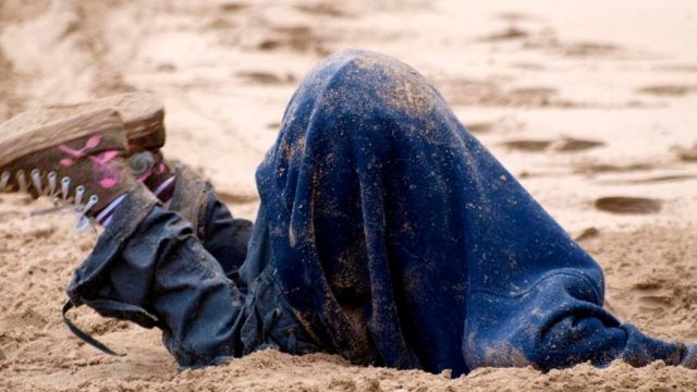 Una persona enterrando la cabeza en la arena