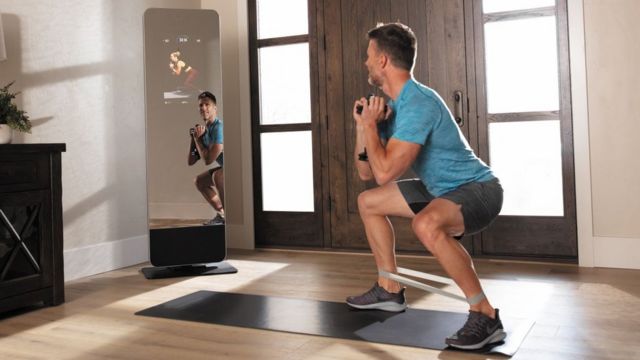 A man exercises with a smart fitness mirror
