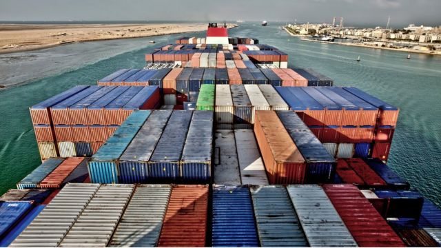 View across the deck of a container ship entering the Suez Canal, Egypt, (with the city of Suez at upper right)