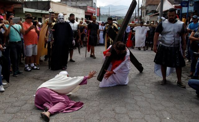 Persona cargando una cruz representando la "vía crucis".