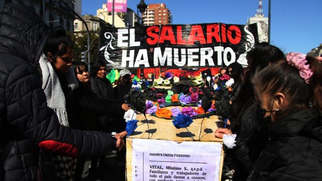 Una simbólica "procesión funeraria" para los salarios en Buenos Aires, un cartel señala "el salario ha mueto".