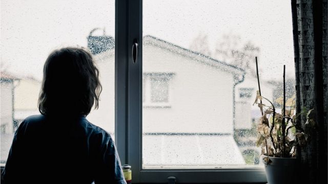 Persona de espaldas asomada a la ventana