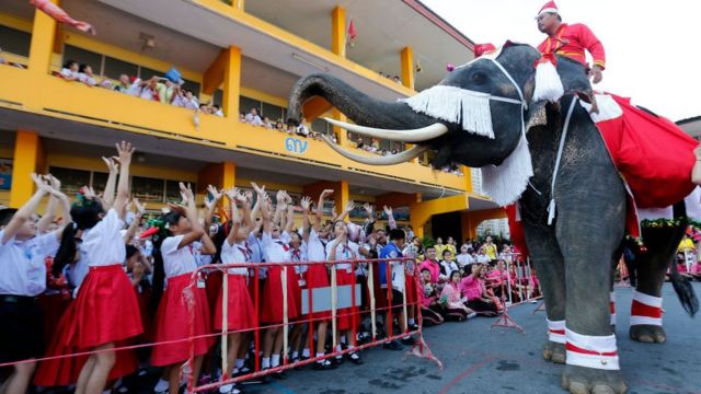 Des enfants très heureux de voir le Père Noël sur un éléphant en Thaïlande.