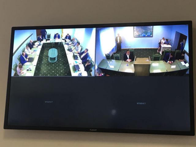 Журналісти дивляться засідання комісії на екранах