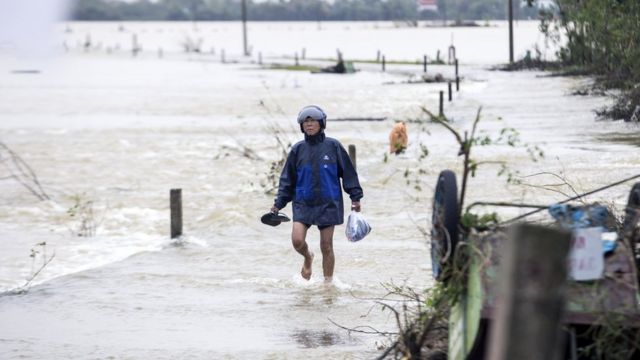 A local resident walks through the floodwater to a pick-up point for relief packages in Quang An Commune, Thua Thien Hue, Vietnam