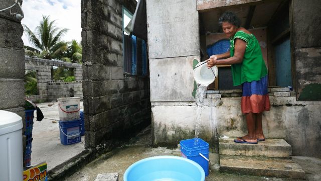 Uma mulher tira água de um tanque de armazenamento