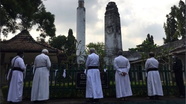 සුදු රිබන් ගැට ගසන ක්‍රිස්තියානි පූජකවරු