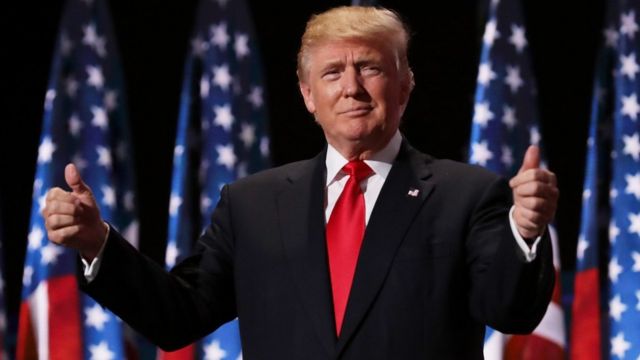 Donald Trump em evento eleitoral sorrindo e com os dois polegares para cima