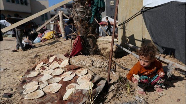 屋外で食事をとる子供（6日、ガザ地区南部ラファの避難民キャンプ）