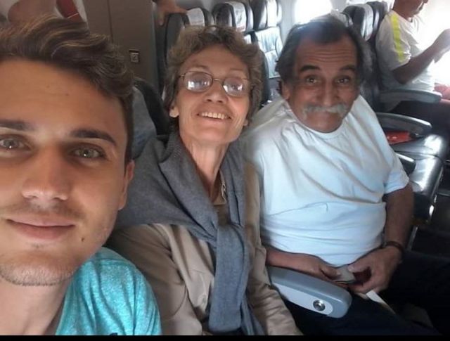 Imagem mostra Pedro Giles, de 24 anos, a mãe, Sueli, e o pai, o músico Lúcio Yanel sentados em poltronas de avião. Sueli tem Alzheimer e o marido faz serenatas para ela todos os dias