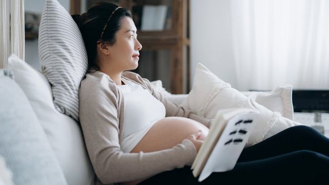 Una mujer asiática embarazada leyendo un libro