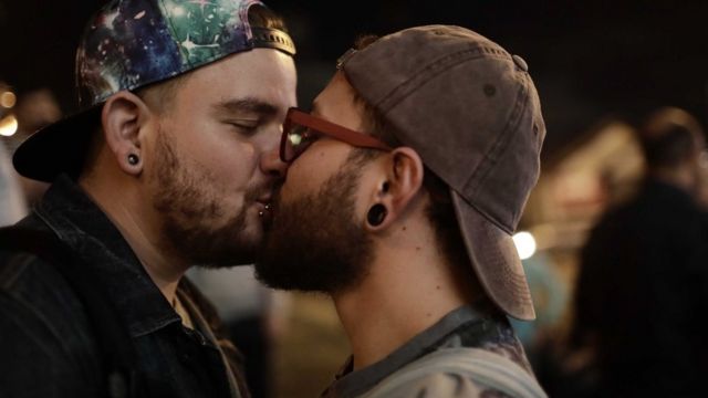 Una pareja de hombres se besa.