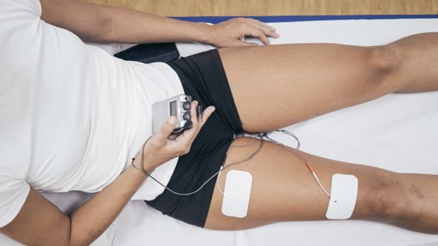 A woman using a muscle electrical stimulation system.