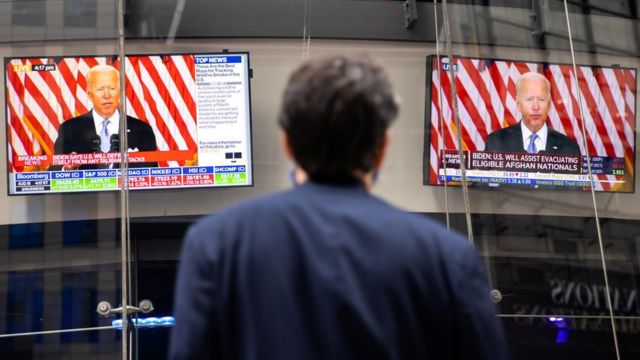 أمريكي يتابع خطاب لبايدن عبر شاشات تلفزيون في الشارع