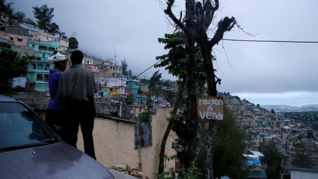 Many Haitians live in flimsy huts vulnerable to flooding. The sign reads "house for sale"
