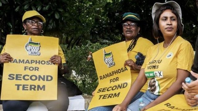 Supporters of South African President Cyril Ramaphosa gestures against Carl Niehaus (not framed), veteran member of the African National Congress (ANC) outside the NASREC Centre in Johannesburg, on December 05, 2022 before the start of a National Executive Committee (NEC) meeting of the Africa National Congress (ANC) to discuss the fate of the Presiden