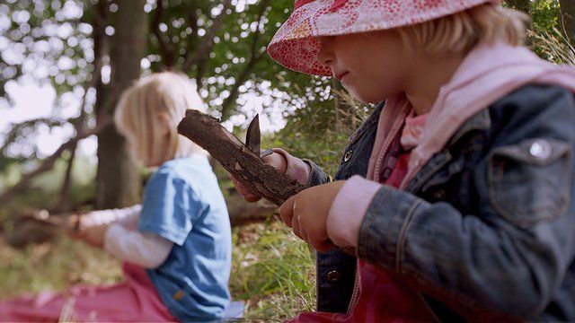 Criança usa faca para cortar madeira em cena do documentário "Nature Play"