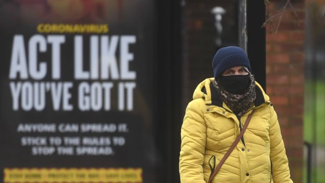 Woman at a bus stop in a mask