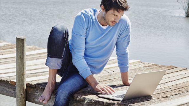 A man with a laptop on the dock