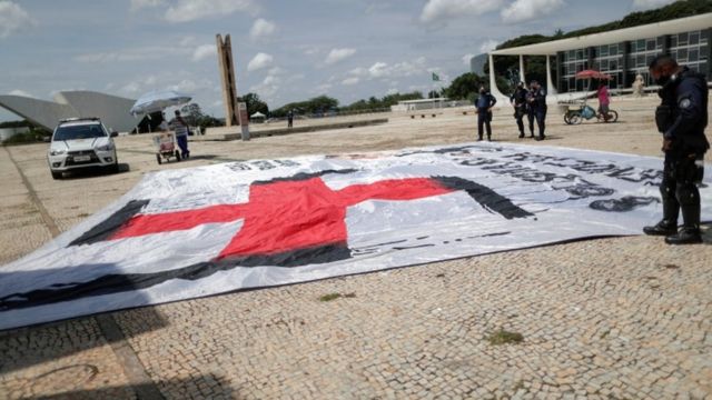 Policial observando bandeira com símbolonazista com imagem de Bolsonaro