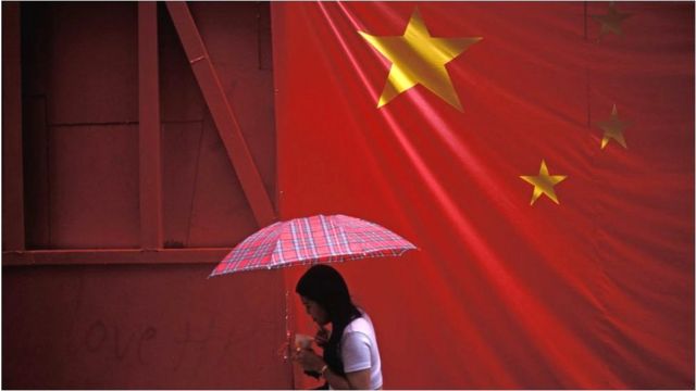 A large banner Chinese flag hangs over a pedestrian on the eve of the handover of sovereignty from Britain to China, on 30 June 1997, in Hong Kong, China.