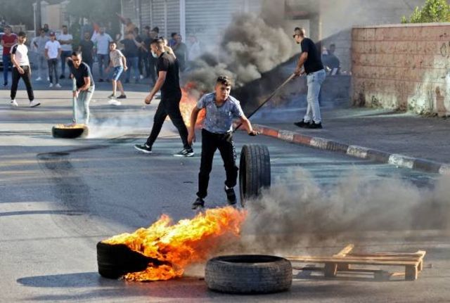 شبان فلسطينيون يحرقون إطارات السيارات في القدس احتجاجاً على المسيرة.