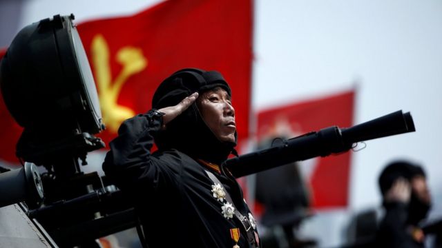 North Korean soldier saluting in front of a flag