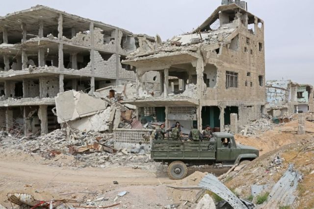القوات الحكومية تمر بالقرب من الأبنية المدمرة في منطقة جوبر في الغوطة الشرقية في 3 أبريل / نيسان 2018.