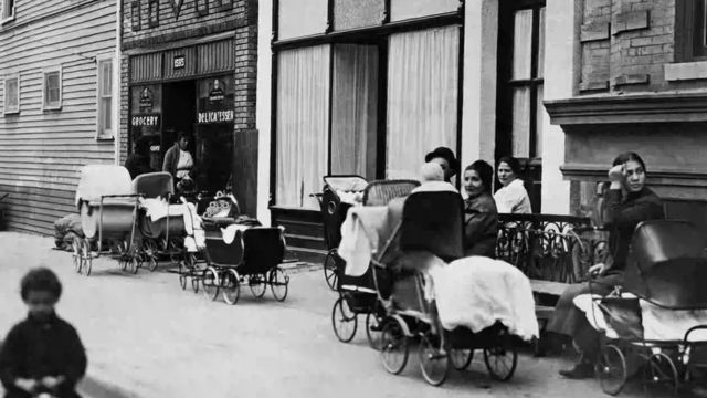 Des femmes et des hommes assis avec des poussettes devant la clinique Sanger