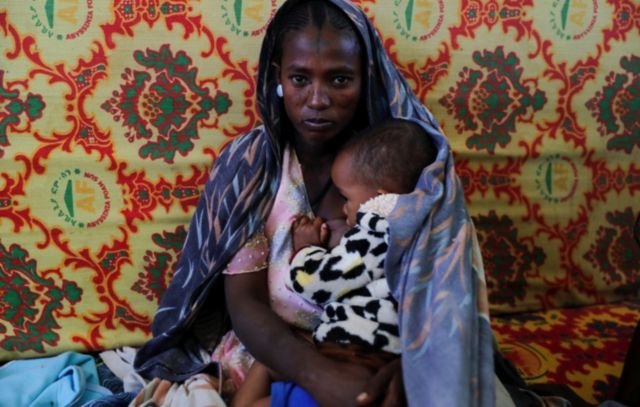 Uma mulher segura uma criança dentro da escola secundária de Adiha, que virou abrigo temporário para pessoas deslocadas pelo conflito, na cidade de Mekelle, região de Tigre, Etiópia, em 12 de março de 2021