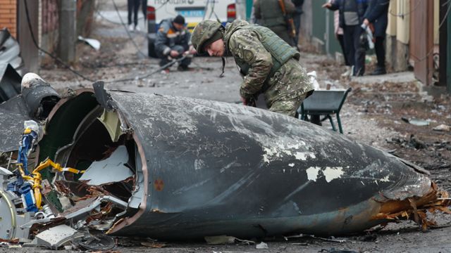 Tentara memerikisa puing pesawat yang ditembak jatuh di Kyiv.